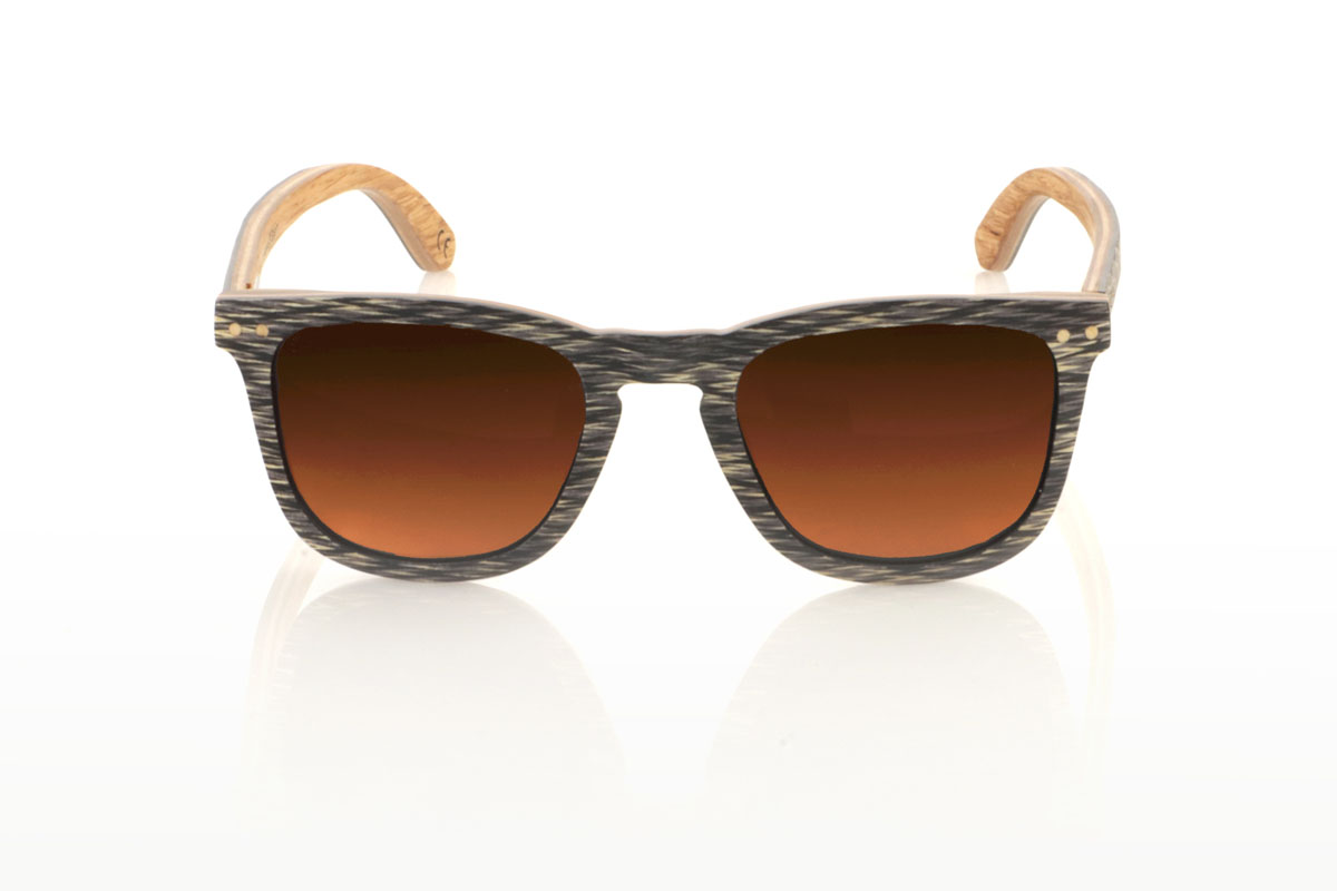 Wood eyewear of Jichimu RISKY. RISKY wooden sunglasses combine a classic shape that flatters all face types with a more contained size, creating a versatile and always on-trend accessory. They are meticulously manufactured using a three-strip laminate technique: black Chicken Wing wood on the outside, maple in the center that provides luminosity, and oak on the inside, offering exceptional resistance. The temples replicate this tricolor pattern, guaranteeing coherence and style throughout the entire set. What really makes the RISKY stand out is the unique texture of its front, accented with eye-catching oak rivets. Measuring 140x47mm and a caliber of 49, these glasses are the perfect balance between comfort and style statement. for Wholesale & Retail | Root Sunglasses® 